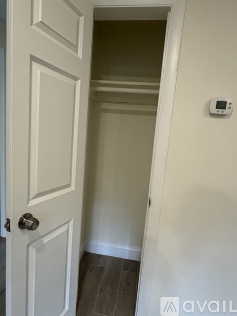 A white door with a silver handle and a small white device on the wall.