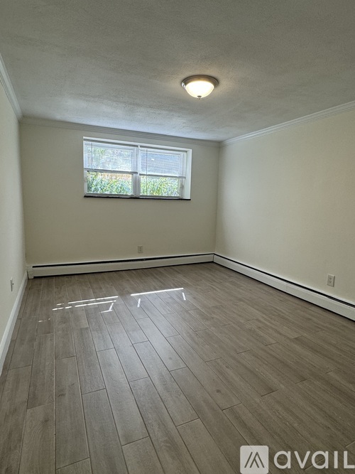 A room with a window and wooden flooring.