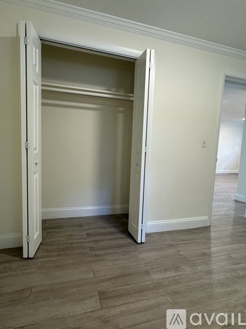 A room with a white door and wooden flooring.