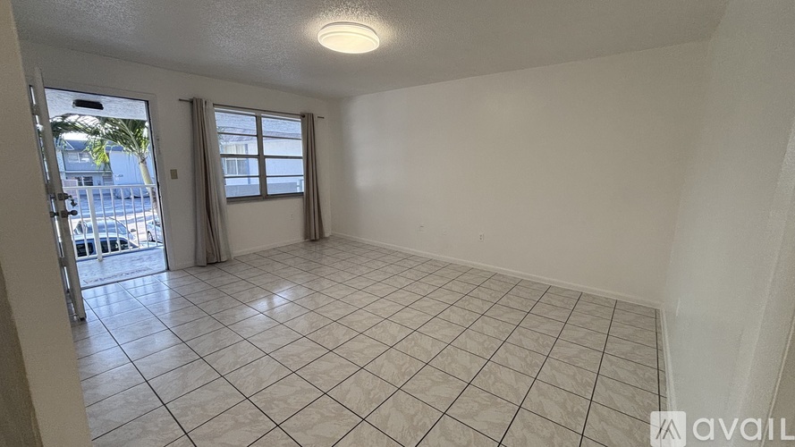 A room with tiled flooring and a sliding glass door leading to a balcony.