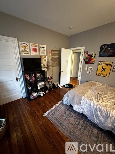 A bedroom with a bed, a dresser, and a wall with pictures and a caution sign.