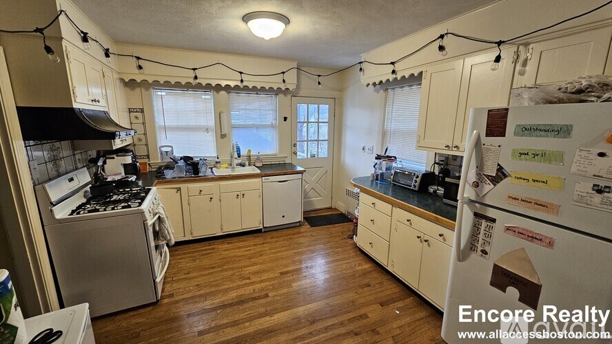 A kitchen with wooden floors and white cabinets.