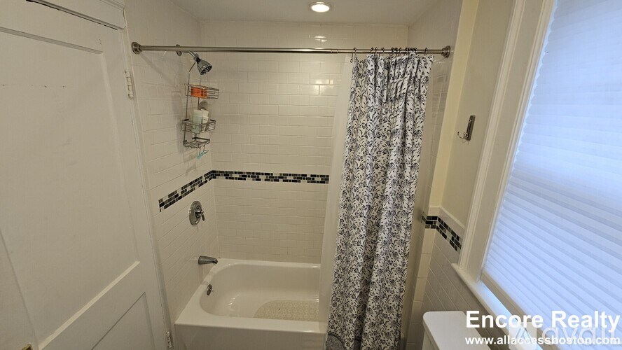 A white bathroom with a black and white tile shower.