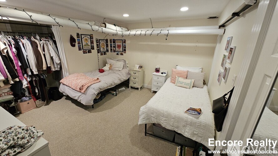 A bedroom with two beds and a closet full of clothes.