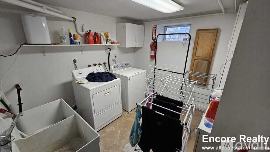 A laundry room with a washer and dryer, ironing board, and ironing rack.