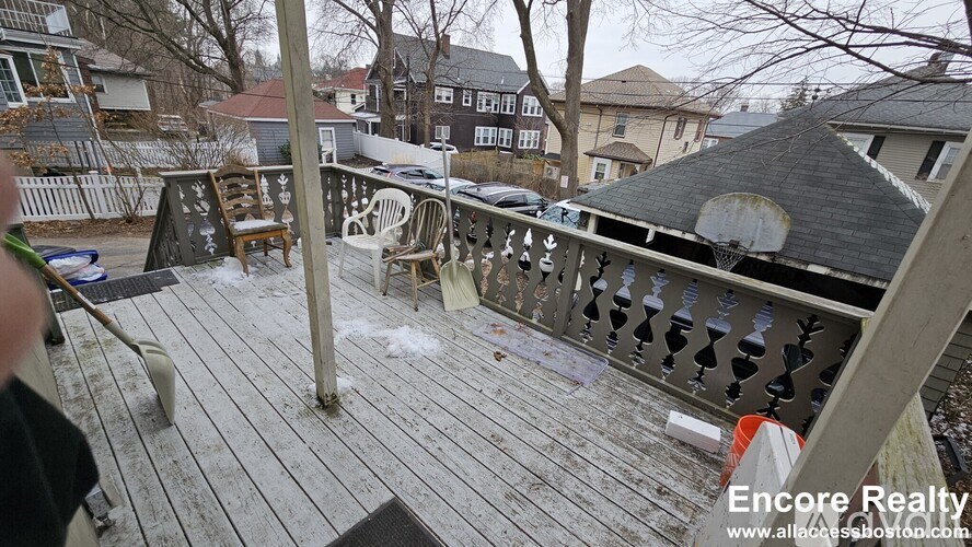 A deck with a table and chairs is in front of a house.
