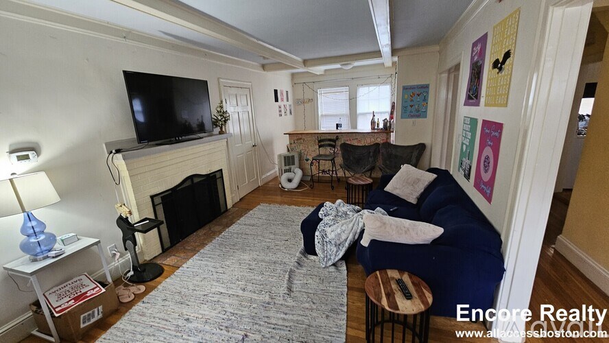 A living room with a fireplace and a television on the wall.