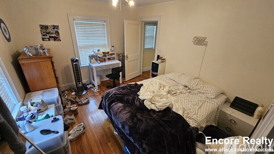 A messy bedroom with a bed, desk, and chair.