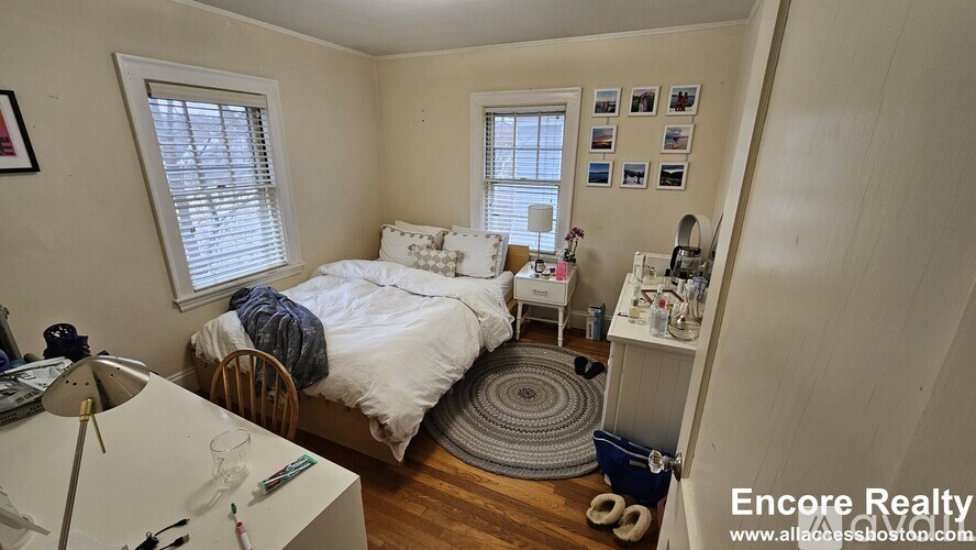 A bedroom with a bed, desk, and window.