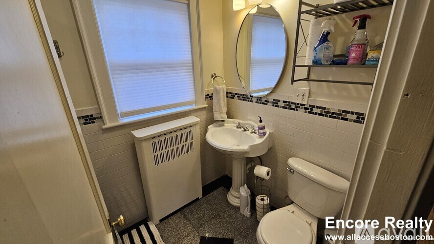 A bathroom with a toilet, sink, and window.