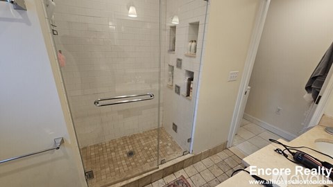 A shower with a glass door and a tiled floor.