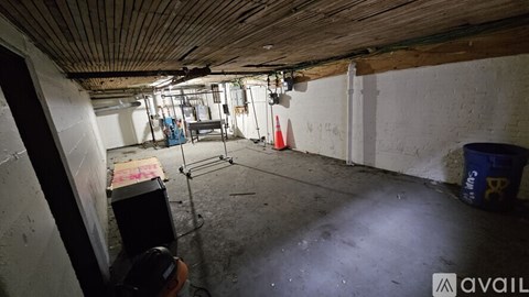 A room with a wooden ceiling and white walls, containing a variety of items including a blue bucket and a red and white striped cone.