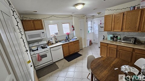 A kitchen with white appliances and wooden cabinets.