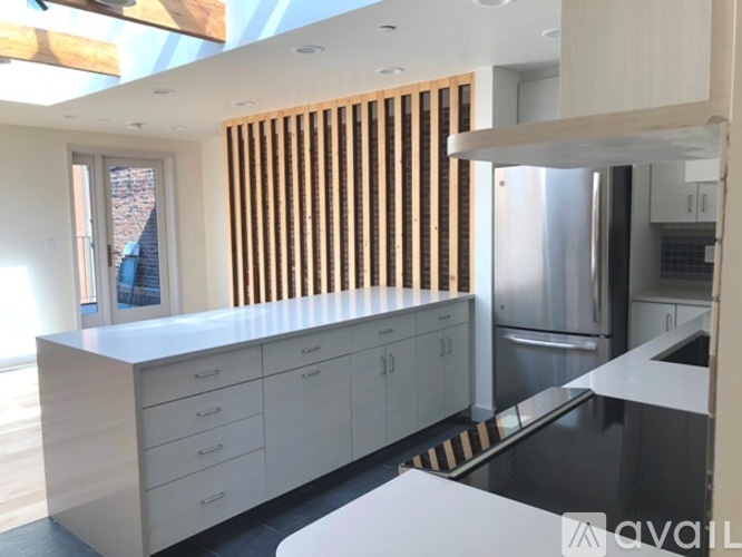 A modern kitchen with white cabinets and a wooden slat window.