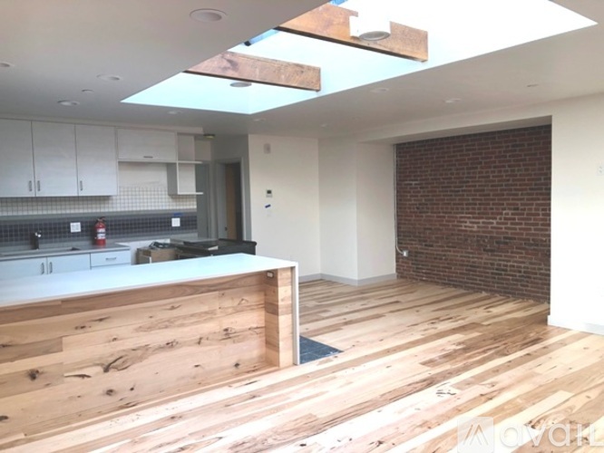 A kitchen with wooden floors and a brick wall.