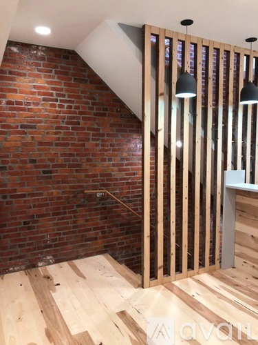 A room with a wooden floor and a brick wall.