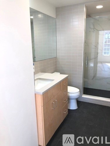 A bathroom with a toilet, sink, and a glass shower door.