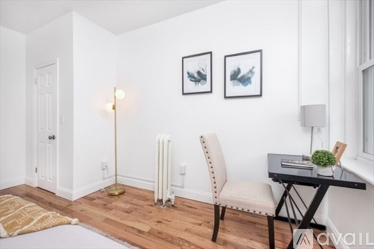 A room with a chair, a table, and two framed pictures on the wall.