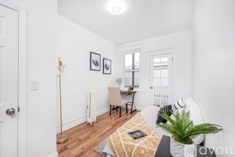 A living room with a couch, a chair, a table, a potted plant, and pictures on the wall.
