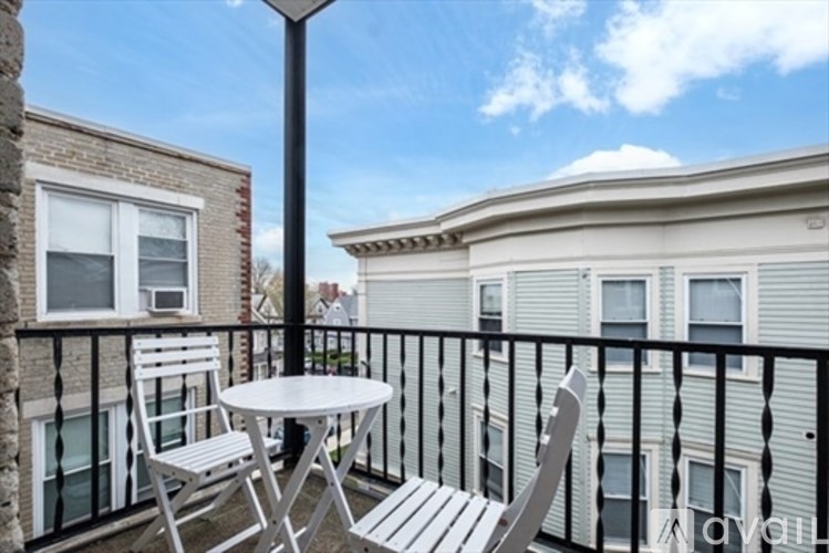 A balcony with a table and chairs overlooks a building.
