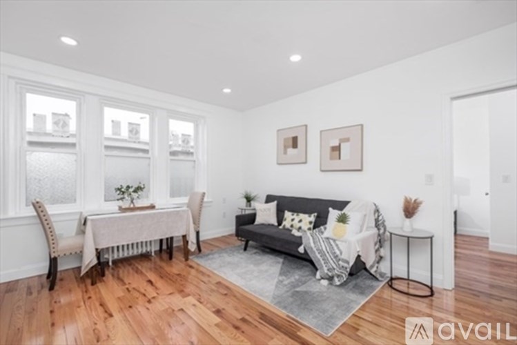 A living room with a grey couch, a dining table with chairs, and a rug.