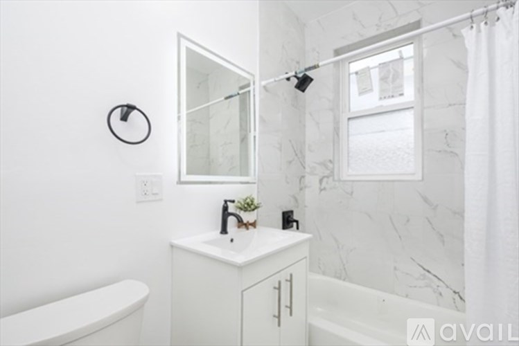 A white bathroom with a tub, sink, mirror, and a window.