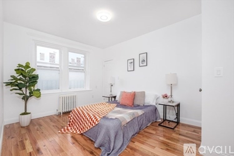 A bedroom with a bed, a potted plant, and a window.