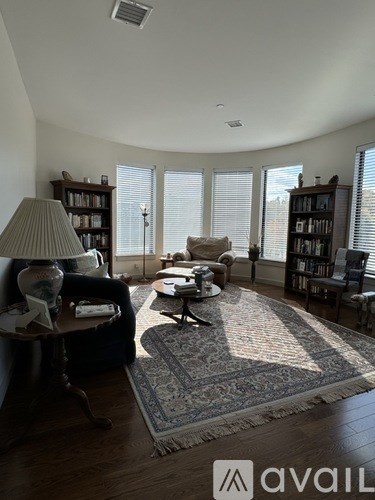 A living room with a rug, a lamp, a sofa, and a bookshelf.