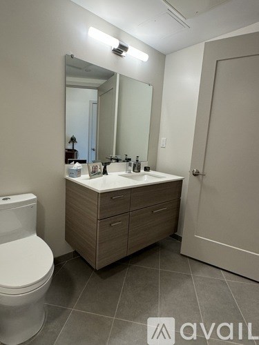 A bathroom with a toilet, sink, mirror, and a white door.