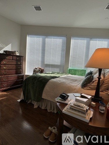 A bedroom with a bed, a nightstand, and a window with blinds.