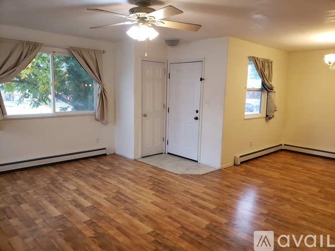 A room with a ceiling fan and wooden flooring.