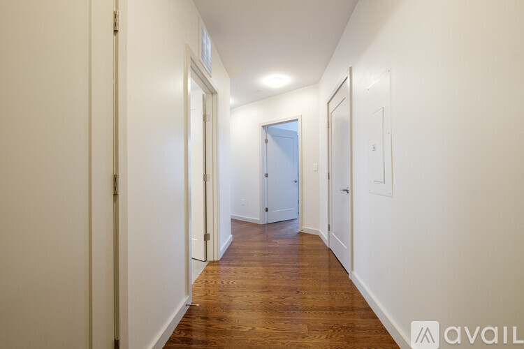 A long hallway with doors on both sides and a wooden floor.
