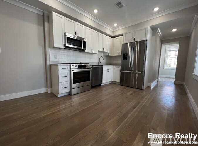A kitchen with wood floors and stainless steel appliances.