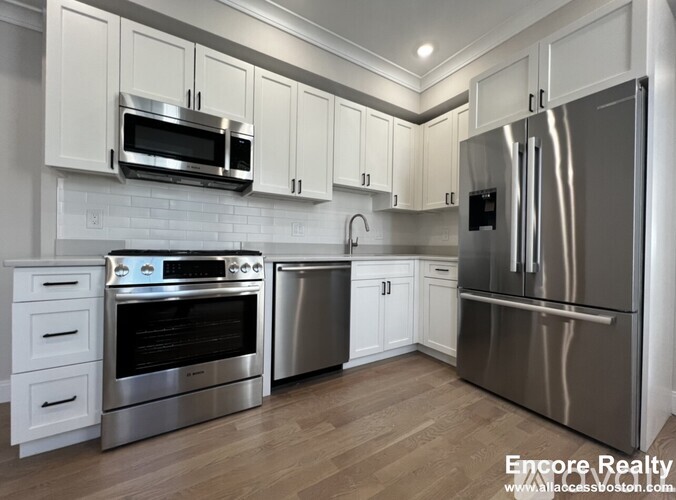 A modern kitchen with stainless steel appliances and white cabinets.