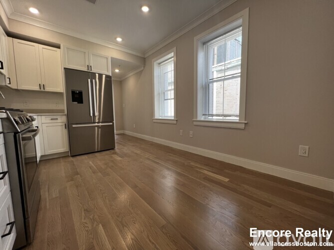 A kitchen with wood floors and a stainless steel refrigerator.