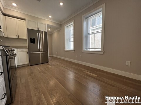A kitchen with wood floors and a stainless steel refrigerator.