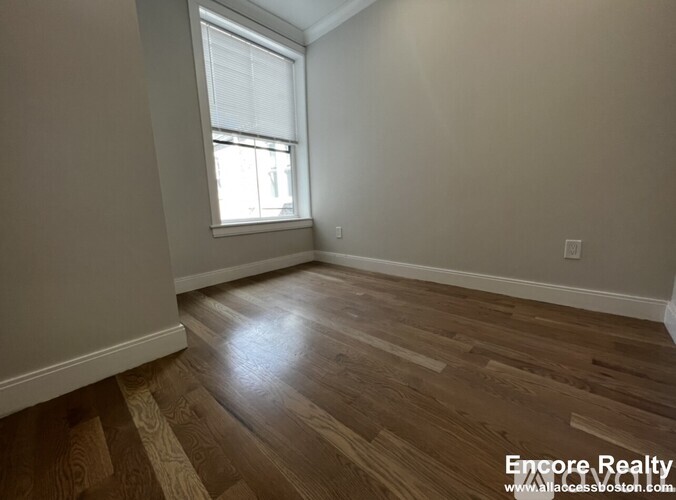 A room with wooden flooring and a window.