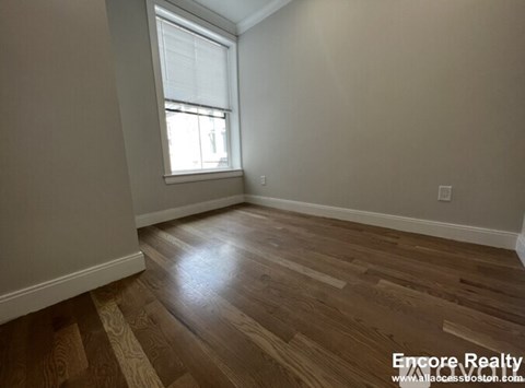 A room with wooden flooring and a window.