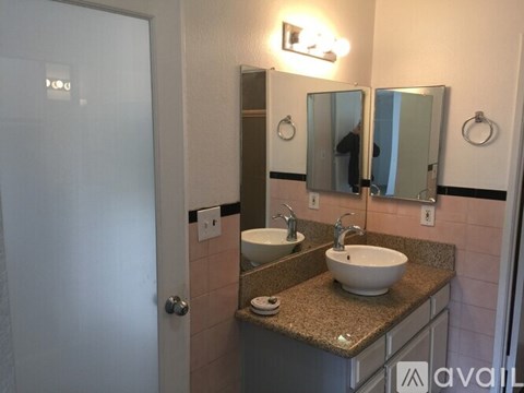 A bathroom with a sink, mirrors, and a door.