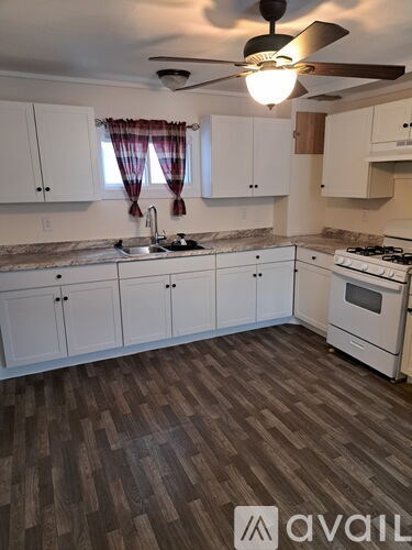 A kitchen with white cabinets and a wooden floor.