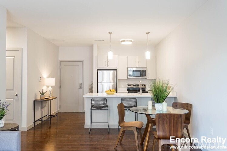 A dining room with a table set for two and a kitchen area in the background.