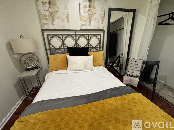 A bed with a white comforter and a yellow blanket is in the foreground of the image.