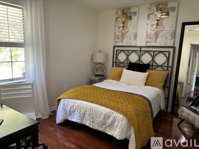 A bedroom with a bed covered in a yellow comforter.