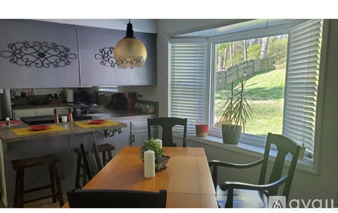A kitchen with a table and chairs in front of a window.