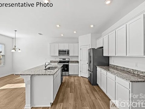 A modern kitchen with white cabinets and a granite countertop.