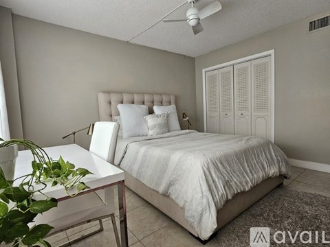 A bedroom with a bed, a table, and a plant.