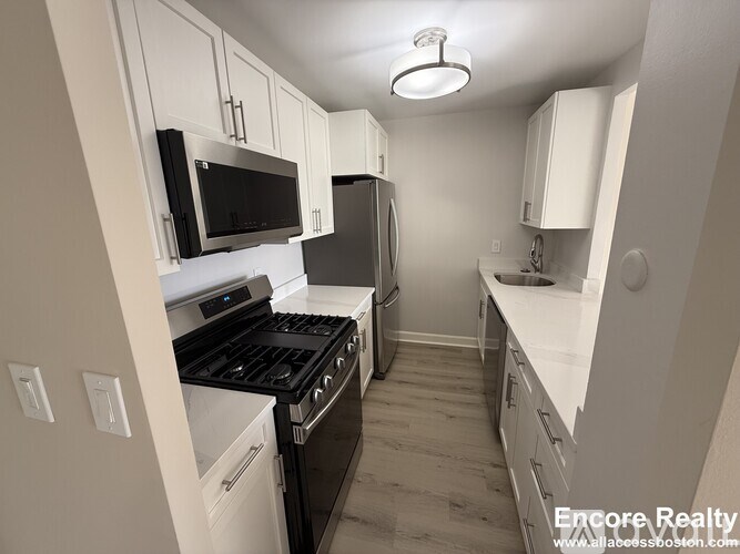 A kitchen with white cabinets and black appliances.