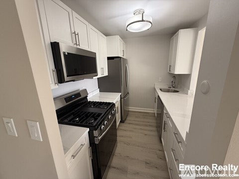 A kitchen with white cabinets and black appliances.