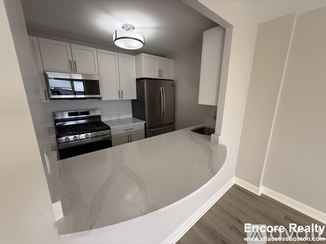 A kitchen with a refrigerator, oven, and microwave.