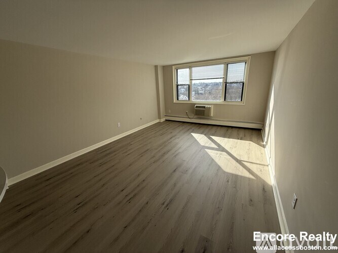 A room with wooden flooring and a window overlooking a snowy landscape.